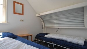 Une chambre avec un lit superposé, une petite table et une fenêtre avec des stores.