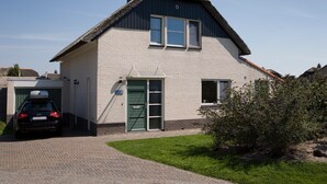 Une maison à deux étages avec un toit de chaume, un garage et une pelouse bien entretenue.