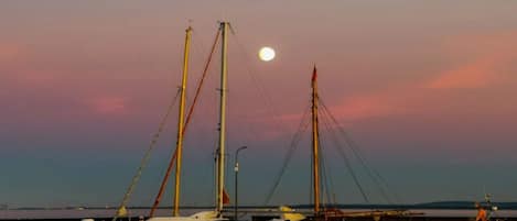 A marina with several sailboats docked at wooden piers under a twilight sky.