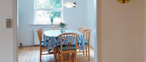 A dining area with a round table, chairs, a window, and a wall clock.