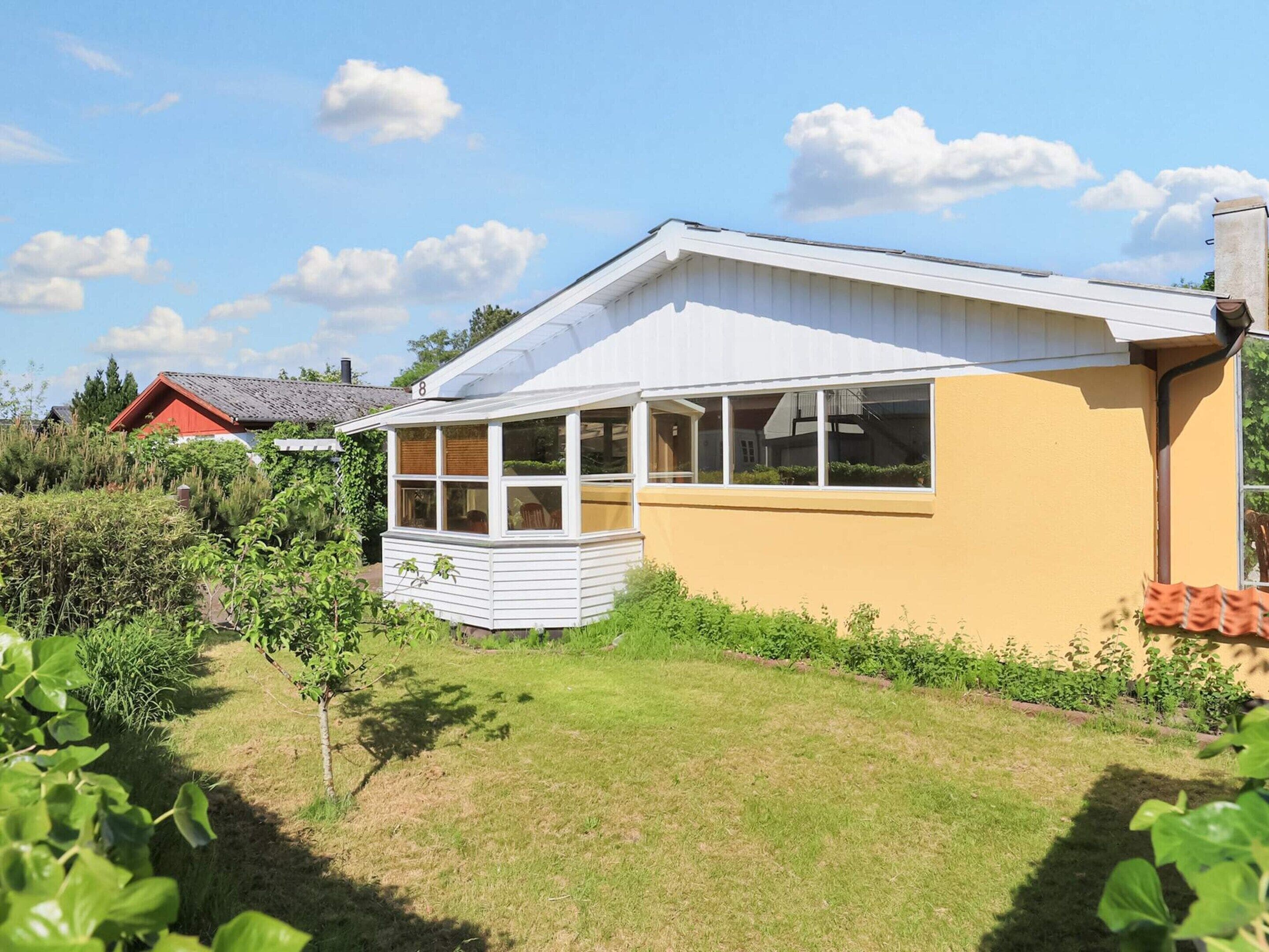 A single-story house with a covered porch, a number '8' on the side, and a garden in the foreground.