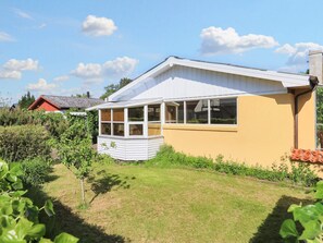 A single-story house with a covered porch, a number '8' on the side, and a garden in the foreground.