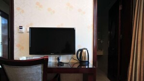 A hotel room with a flat-screen TV, a coffee maker, a chair, and a door leading to another room. - Hongfulou Hostel (Shilin)