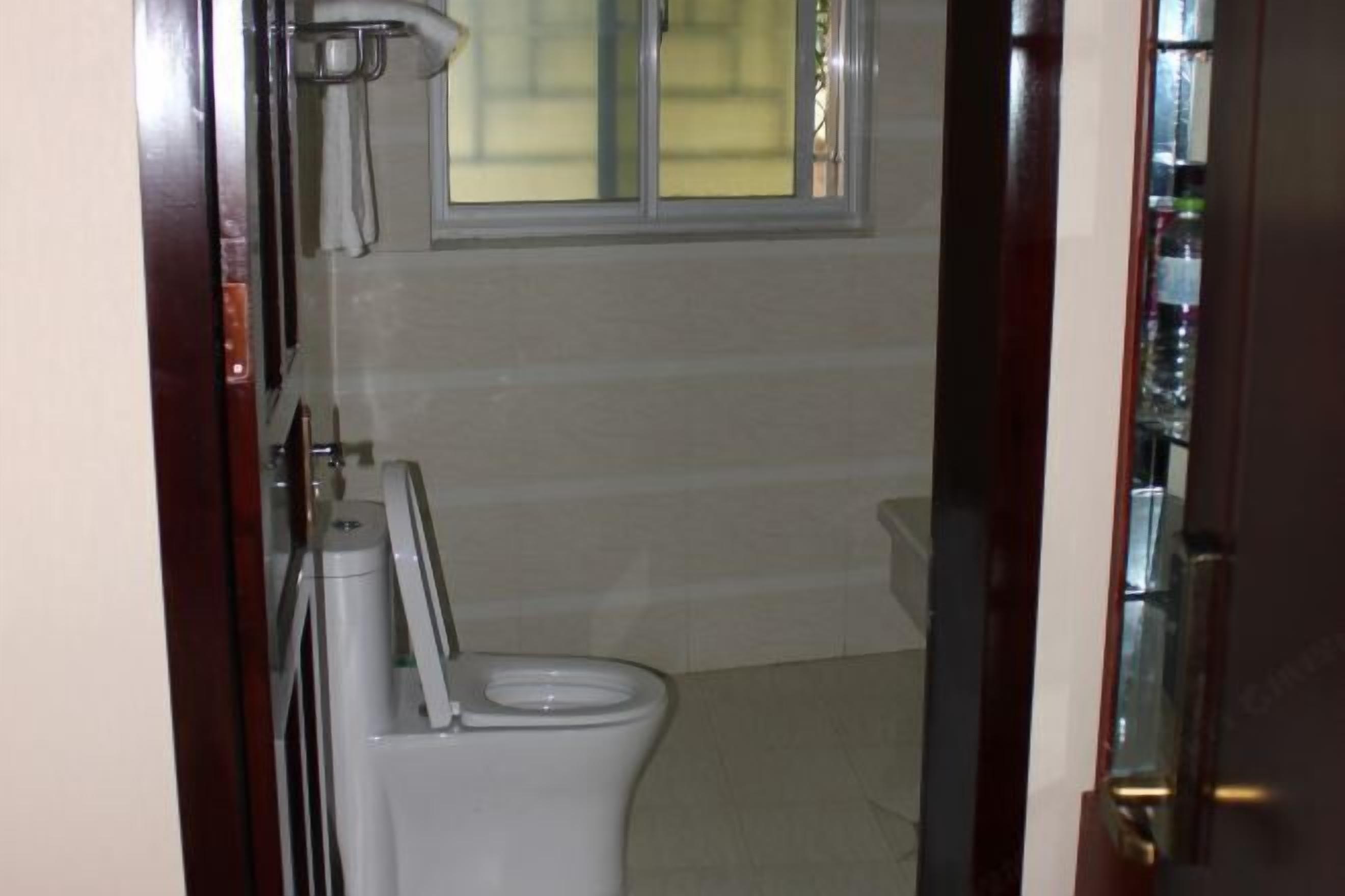 Une petite salle de bain avec des toilettes, un porte-serviettes et une fenêtre.