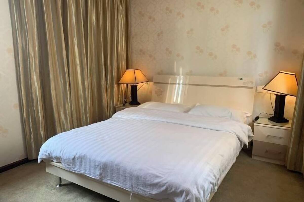 Ein Hotelzimmer mit einem Bett, zwei Nachttischen und einer Lampe auf jeder Seite.