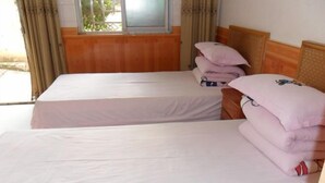 A room with two beds, each with a wooden headboard and a window. There are pillows stacked on one bed. - Hongfulou Hostel (Shilin)