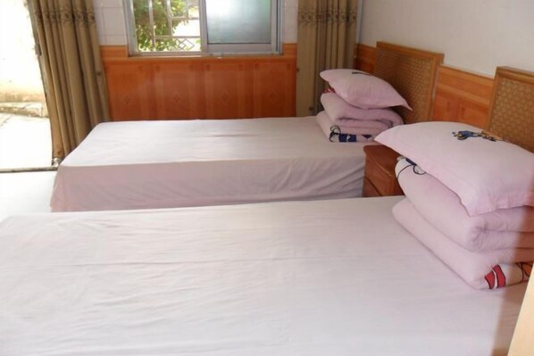 A room with two beds, each with a wooden headboard and a window. There are pillows stacked on one bed. - Hongfulou Hostel (Shilin)