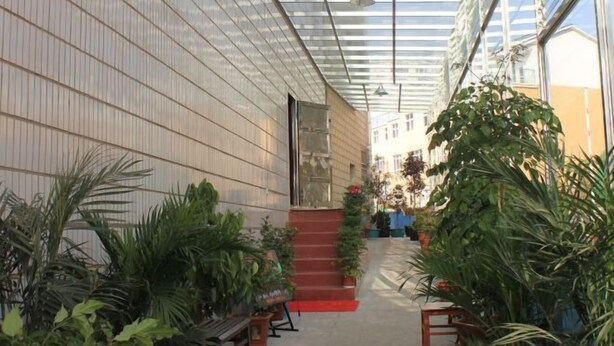 A covered walkway with potted plants, a staircase, and a building with a tiled exterior. - Hongfulou Hostel (Shilin)