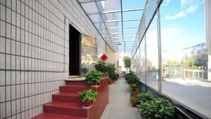 A covered walkway with red steps, potted plants, and a glass ceiling allowing natural light. - Hongfulou Hostel (Shilin)