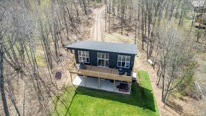 A two-story house with a deck, surrounded by trees. - Escape to Chub Lake Retreat: Waterfront Luxury House in Carlton, Minnesota (Carlton)