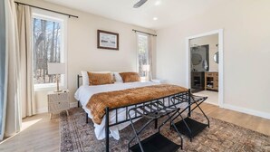 A bedroom with a bed, a window, a bedside table, and a ceiling fan. - Escape to Chub Lake Retreat: Waterfront Luxury House in Carlton, Minnesota (Carlton)