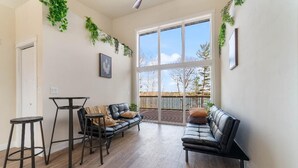 A spacious living area with a large sliding glass door leading to a balcony, furnished with a leather sofa, two chairs, and a coffee table. - Escape to Chub Lake Retreat: Waterfront Luxury House in Carlton, Minnesota (Carlton)