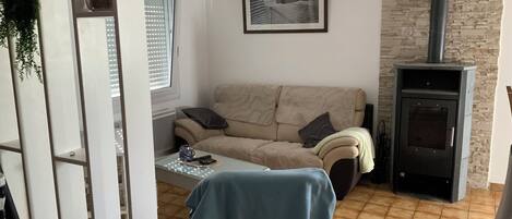 A living room with a sofa, a table with a blue tablecloth, a fireplace, and a framed picture on the wall.