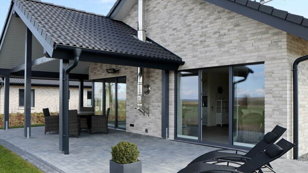 Una casa moderna con un porche cubierto, comedor y sala de estar con mobiliario exterior.