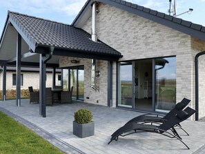 A modern house with a covered patio, a dining area, and a lounge with outdoor seating. - My Baltic Sea Place House by the sea 8 (Niesgrau)