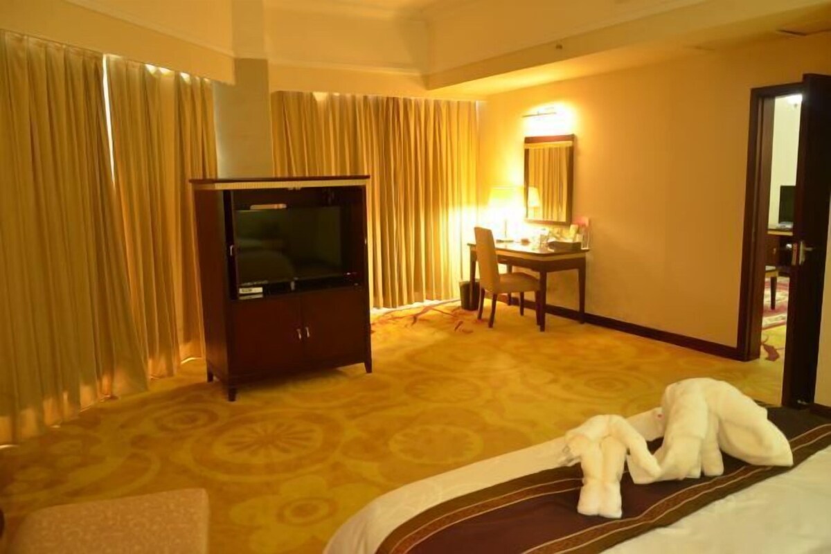 A hotel room with a bed, a TV, a desk, and a chair.