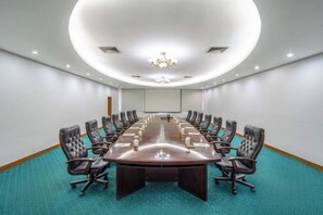 A conference room with a long table, multiple chairs, a projector screen, and a carpeted floor. - Conch International Hotel (Yingde)