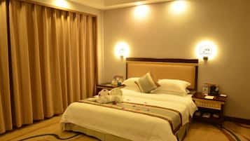 Een hotelkamer met een groot bed, twee nachtkastjes, een lamp en een gordijn.