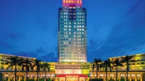 A tall hotel with multiple floors, a prominent sign at the top, and a well-lit facade. - Conch International Hotel (Yingde)