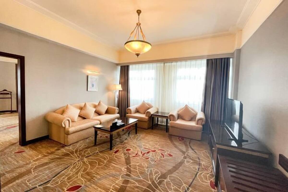 A hotel room with a sofa set, a coffee table, a TV, and a piano.
