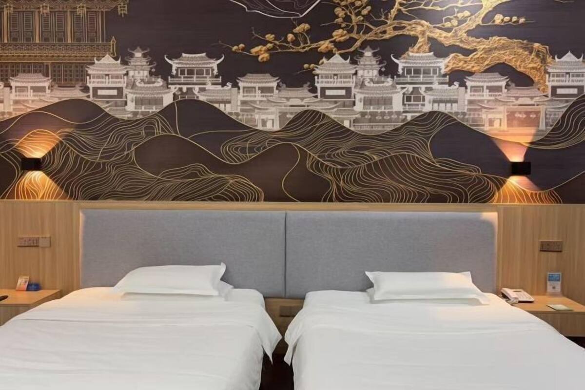 A hotel room with two beds, a decorative wall mural, and bedside lamps.