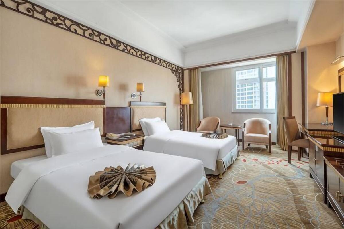 A hotel room with two beds, a TV, a desk, and a chair.