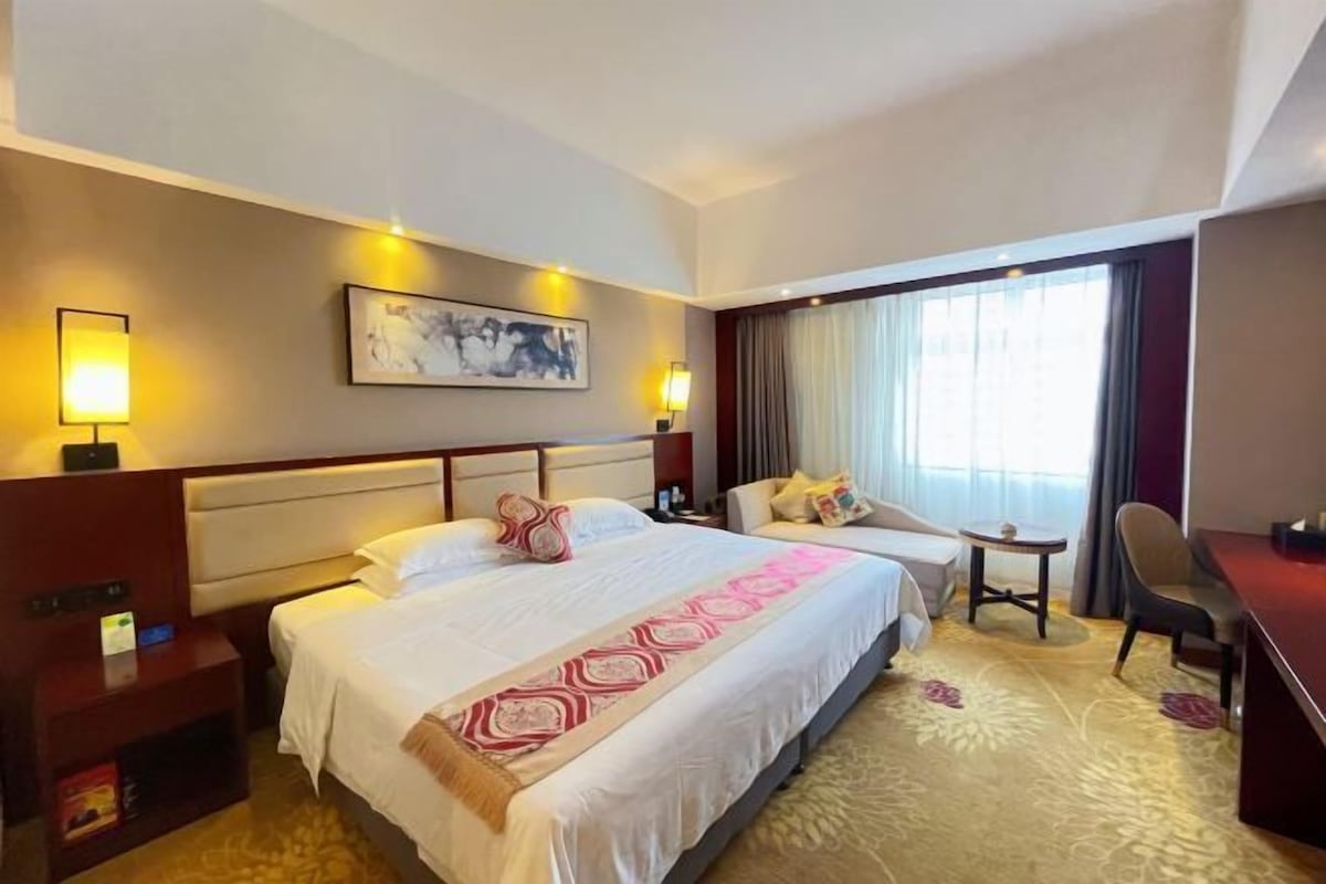 A hotel room with a large bed, bedside tables, a desk, and a chair.