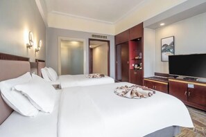 A hotel room with two beds, a television, a wardrobe, and a bathroom visible through an open door.