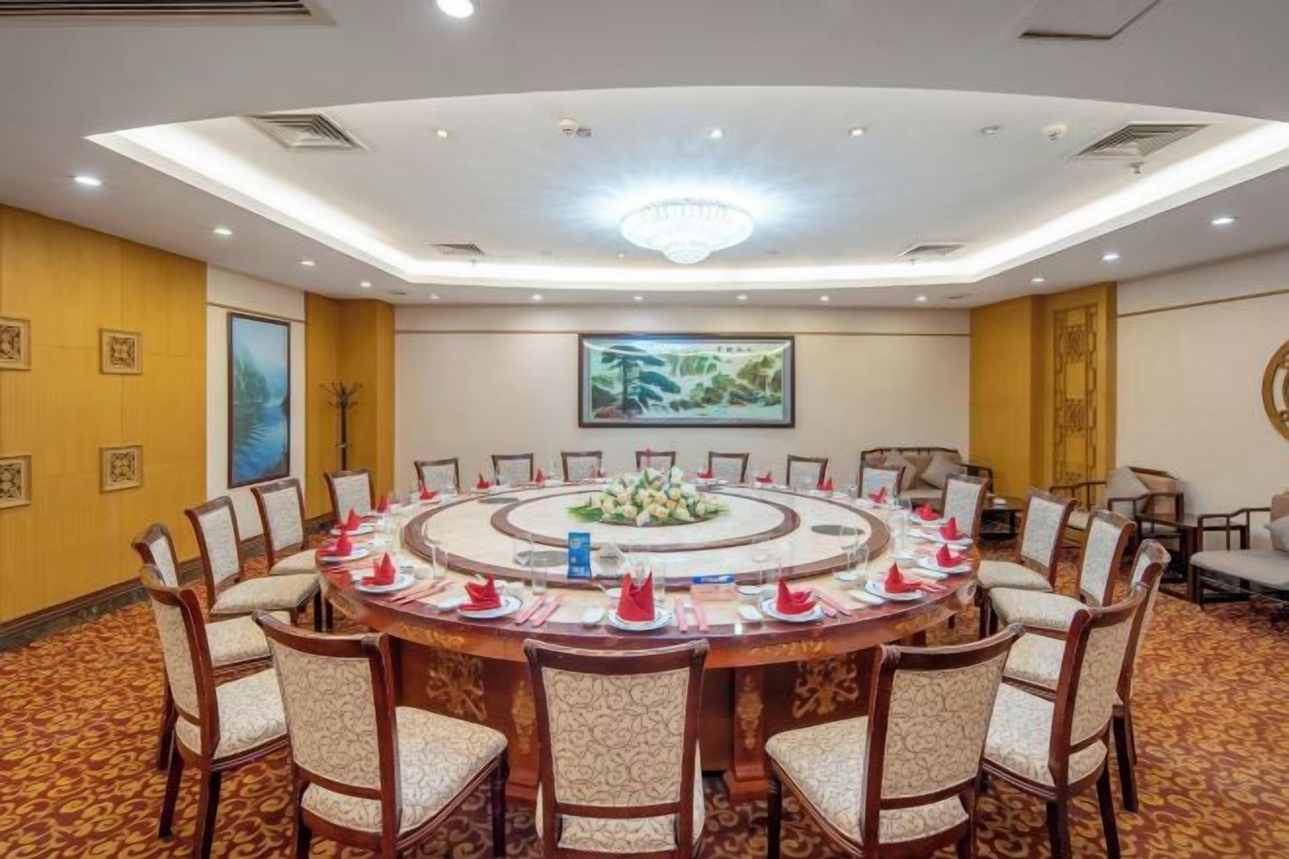 A conference room with a round table, chairs, and a chandelier.