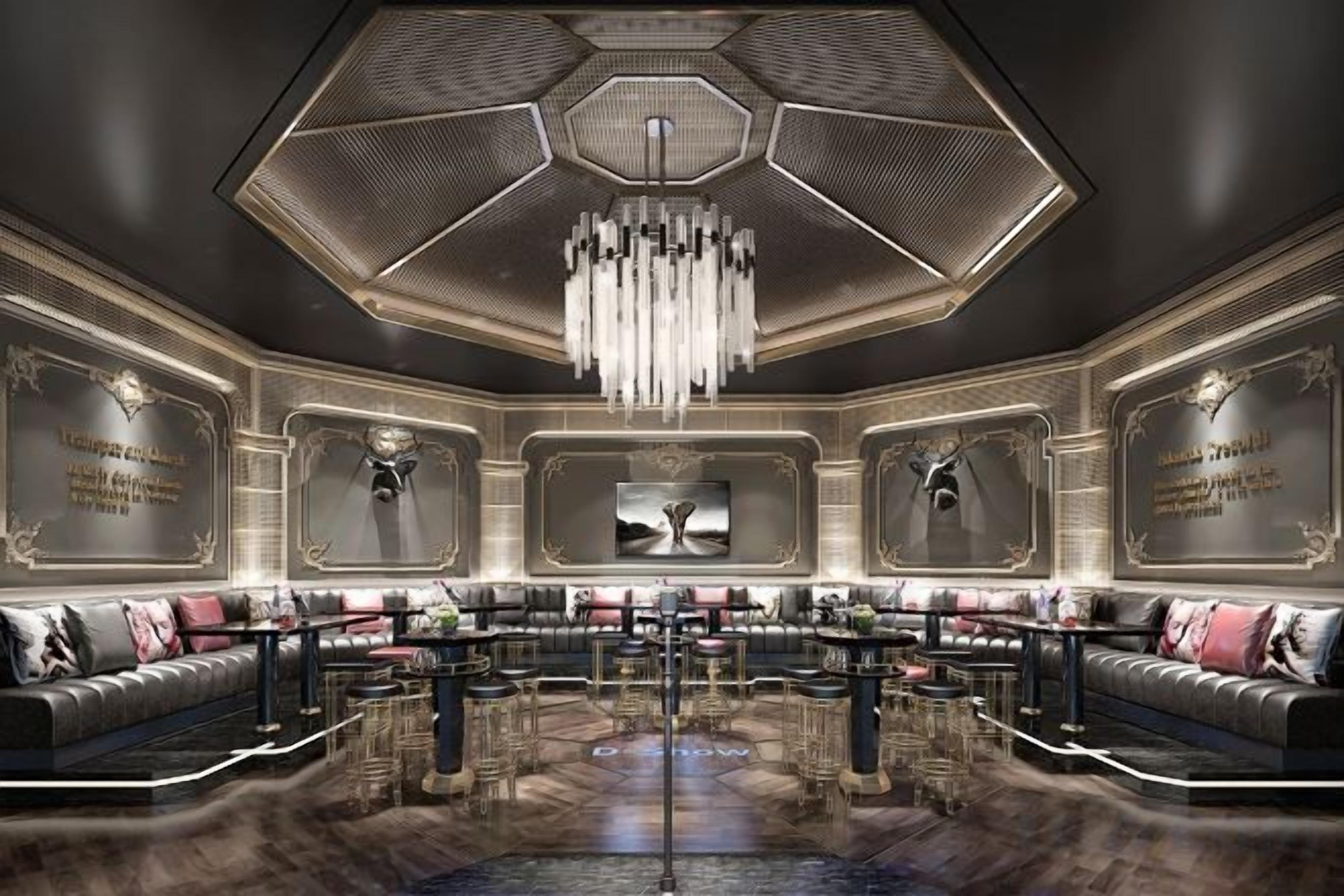 A luxurious lobby with a central seating area, a chandelier, and decorative wall panels.