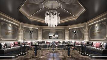 A luxurious lobby with a central seating area, a chandelier, and decorative wall panels.