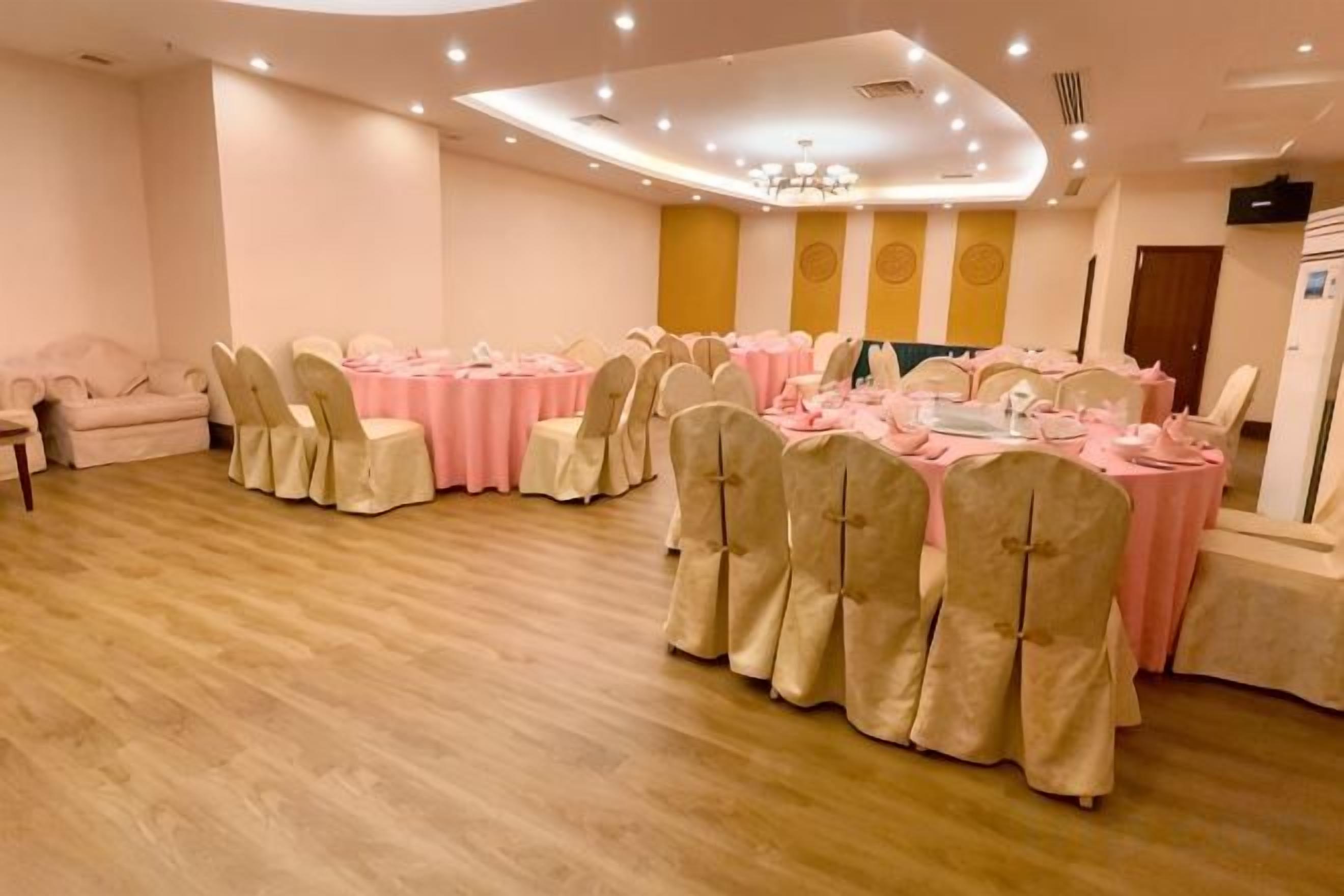 Un salón de banquetes con mesas redondas, sillas y una araña.
