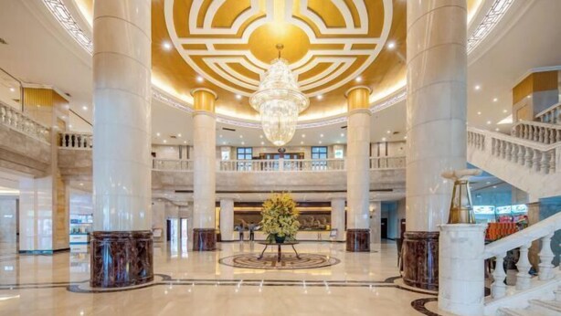 A spacious lobby with marble flooring, a grand chandelier, and a central floral arrangement. - Conch International Hotel (Yingde)