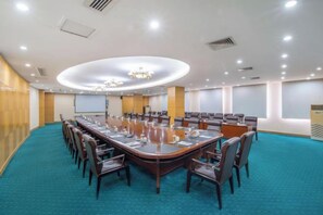 Una sala de conferencias con un escritorio ovalado grande, sillas y una pantalla de proyector.