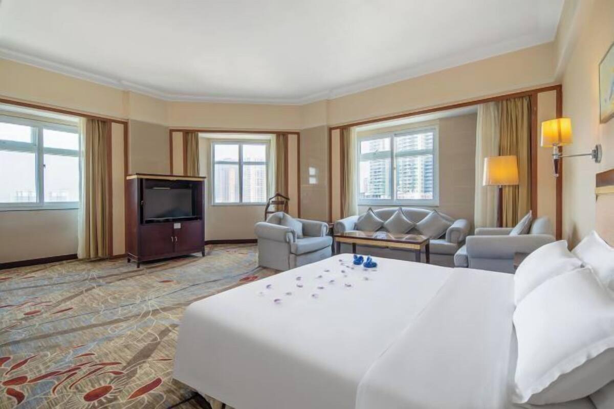 A hotel room with a bed, a television, a sofa, and a desk.