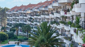 Un hôtel à plusieurs étages doté de balcons, d’une piscine et d’une végétation luxuriante.