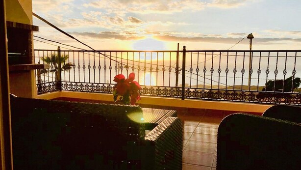 A balcony with a view of the sunset over the sea, featuring a metal railing and a tiled floor. - Belvilla by oyo Home Holidays Casa Rural Tijoco (Adeje)