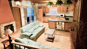 A living room with a sofa, a small table, and a fireplace. There is a kitchen area with cabinets and a microwave. - Belvilla by oyo Home Holidays Casa Rural Tijoco (Adeje)