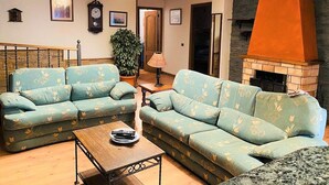 A living room with two light blue sofas, a wooden coffee table, a stone fireplace, and a chandelier. - Belvilla by oyo Home Holidays Casa Rural Tijoco (Adeje)