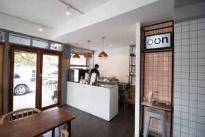 A cafe interior with a counter, seating area, and a person at the counter. - Oon Poshtel X Cafe (Chiang Mai)