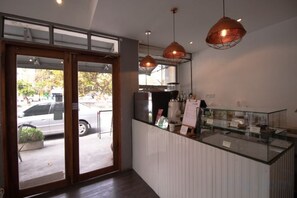 A reception area with a glass counter, a coffee machine, and a hanging pendant light. - Oon Poshtel X Cafe (Chiang Mai)