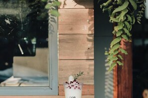A glass of drink with berries and a sprig of rosemary on a wooden surface.