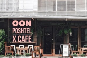 A cafe named 'OON POSHTEL X CAFE' with outdoor seating and a sign indicating it's open. - Oon Poshtel X Cafe (Chiang Mai)