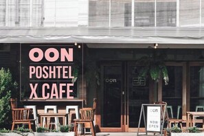 Un café appelé « OON POSHTEL X CAFE » qui dispose de places assises en plein air et d’une enseigne indiquant qu’il est désormais ouvert.