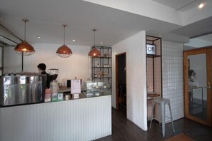 A modern kitchen area with stainless steel appliances, pendant lighting, and a visible counter. - Oon Poshtel X Cafe (Chiang Mai)