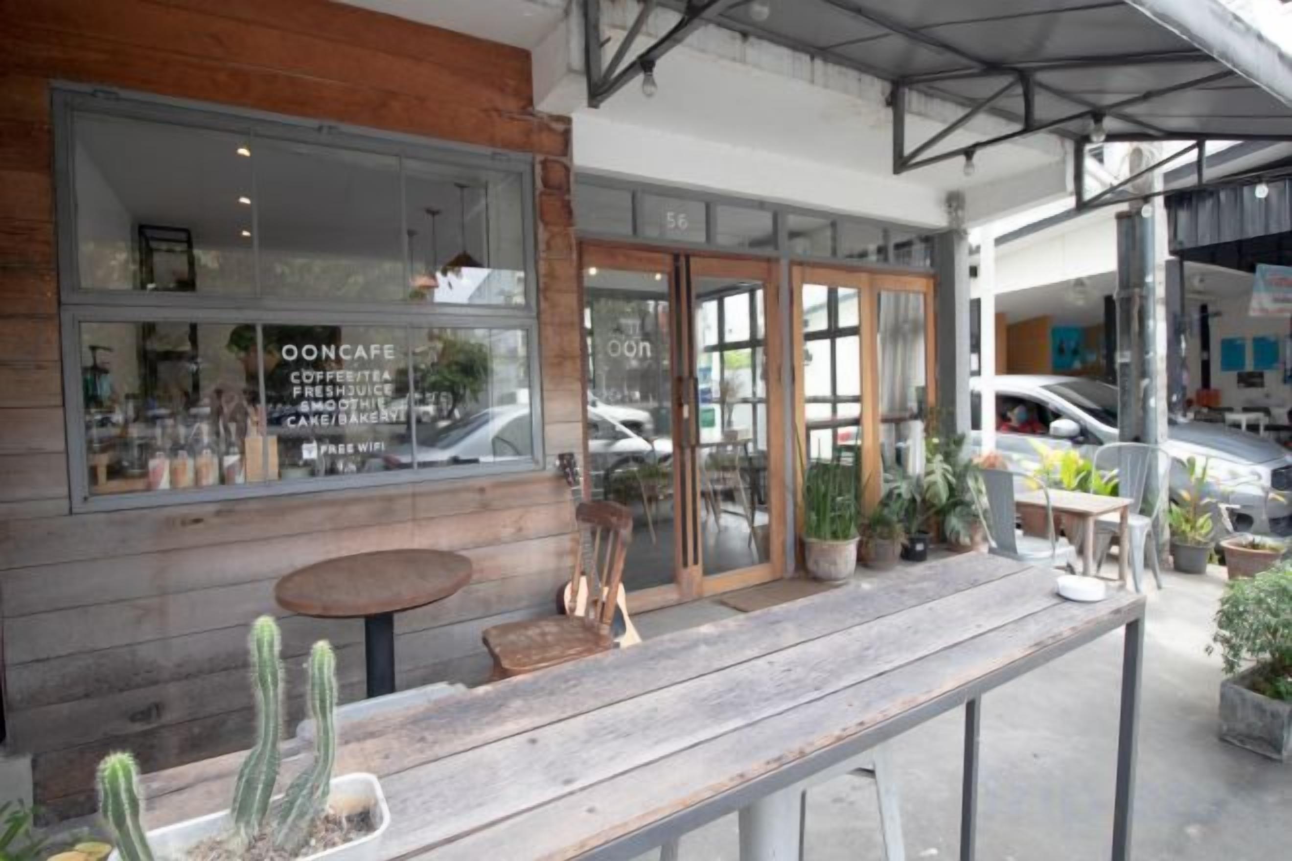 A café with a wooden exterior, large windows, and a patio area with tables and chairs.
