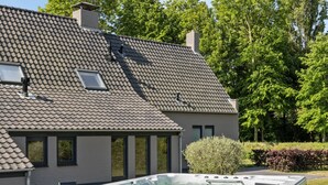 A house with a large hot tub in the backyard, a tiled roof, and a well-maintained lawn. - Wellness Villa With Sauna, spa Near Beach (Ouddorp)