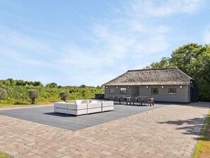 Un edificio con techo de paja y mesas al aire libre, con un patio empedrado.