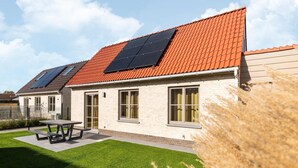 A modern house with a red-tiled roof, solar panels, and a well-maintained lawn. - Holiday Home in Koksijde With Garden & Parking (Koksijde)