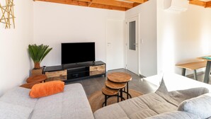 A modern living room with a wooden ceiling, a flat-screen TV, a sofa, and a small table. - Holiday Home in Koksijde With Garden & Parking (Koksijde)